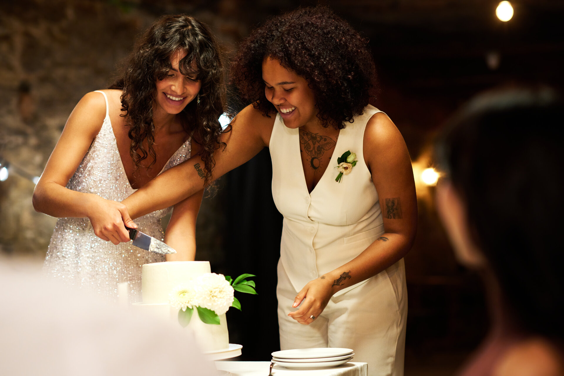 A candid over the shoulder shot of Sara & Jordan cutting their cake.
